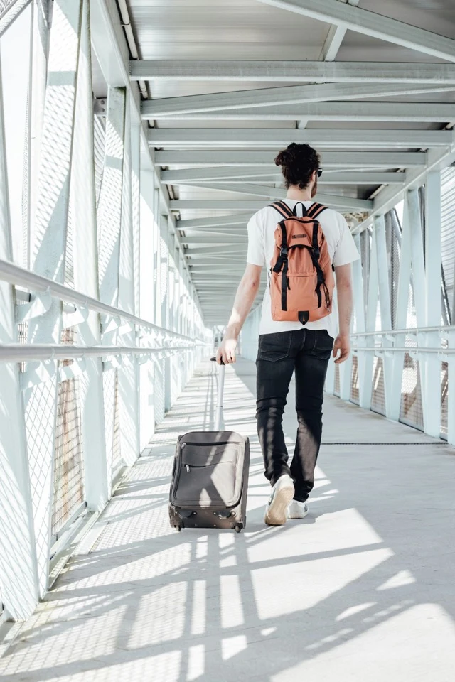A traveller with backpack and luggage on a bridge in China